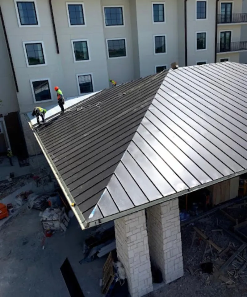 Crew installing standing seam metal roof panels on a commercial project in Northchase